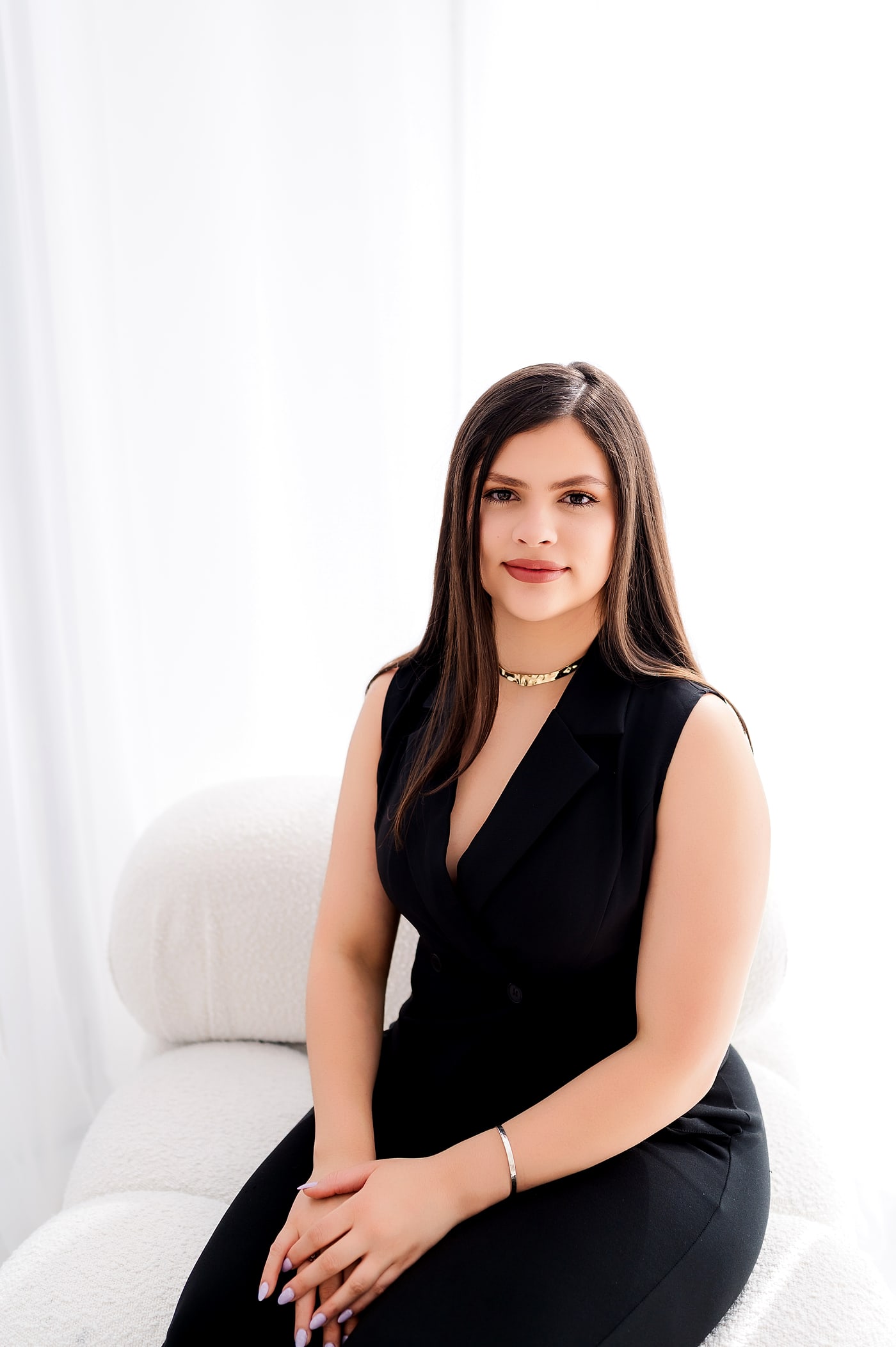 Margo Ruiz, luxury Realtor, seated in a black tailored vest in a bright, airy studio